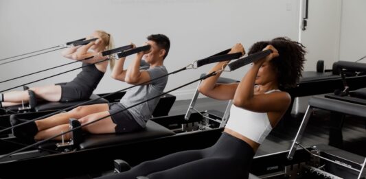 Peloton köper Pilates-startup – kan vara på väg in i reformer-Pilates Grupp av människor tränar pilates på reformer-maskiner