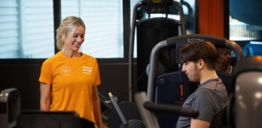 Medley satsar på onboarding – vill höja träningsfrekvensen och förbättra folkhälsan Kvinnlig personlig tränare på Medley instruerar man som styrketränar i maskin